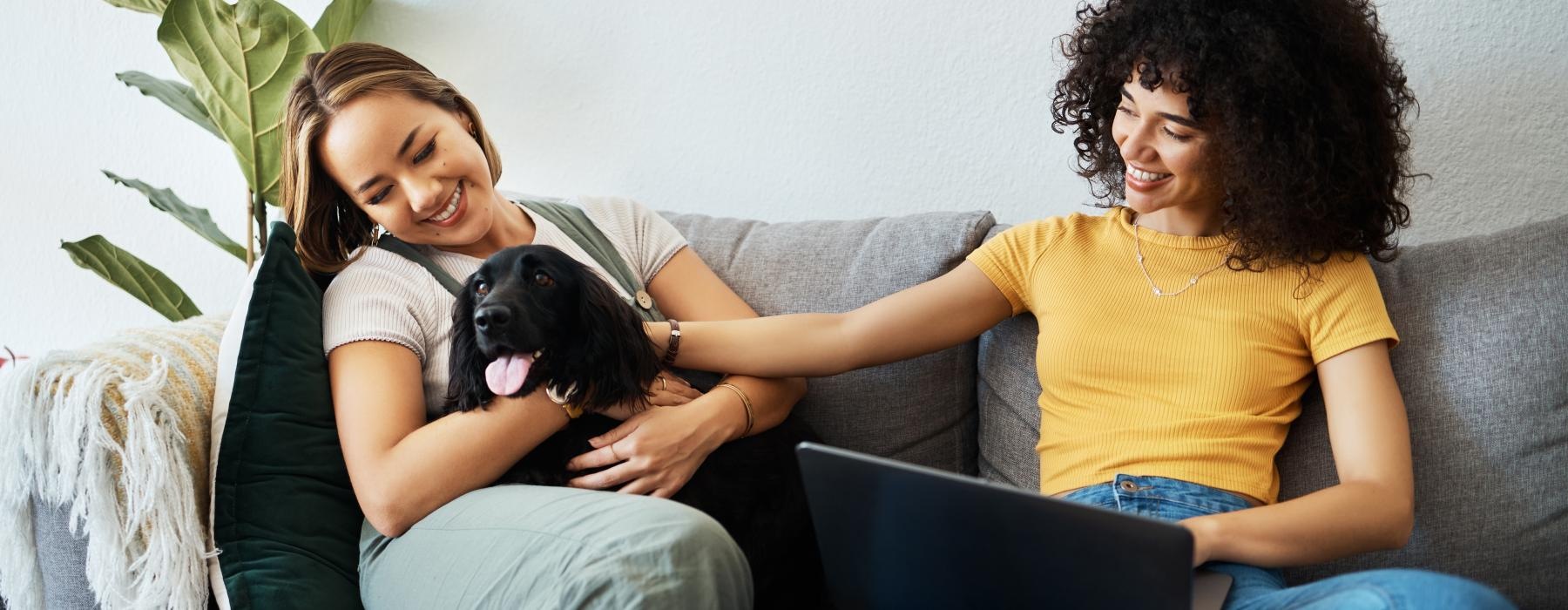 a couple of women sitting on a couch with a dog