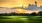 a golf course with trees and a sunset